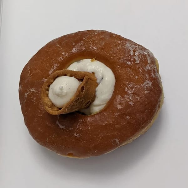 Jupiter Donuts' glazed donut with a swirl of white cream and a crispy pastry curl in the center.
