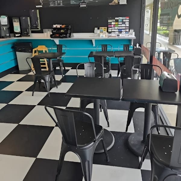 Jupiter Donuts interior with black tables and chairs, a blue counter, and a black and white checkered floor.